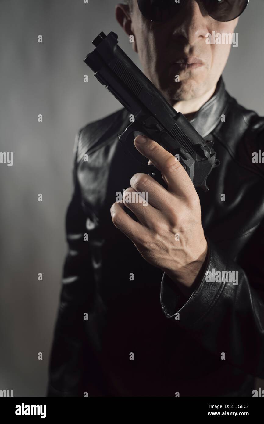 Giacca nera in pelle assassino detective spia assassino assasin con foto ritratto a pistola. Foto Stock