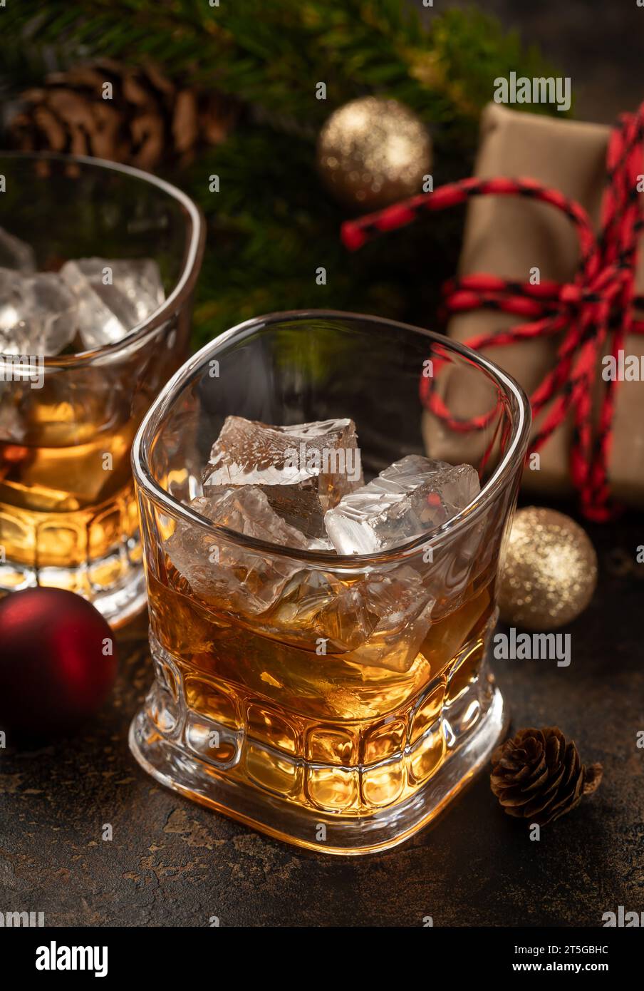 Due bicchieri di whisky e ghiaccio su superficie di legno con decorazioni natalizie sullo sfondo Foto Stock
