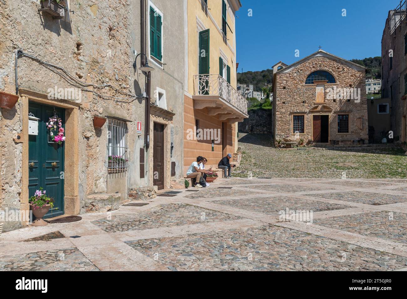 Piazza e chiesa di Sant'Agostino nell'antico borgo in pietra della Riviera Italiana con turisti in primavera, Borgio Verezzi, Savona, Liguria, Italia Foto Stock