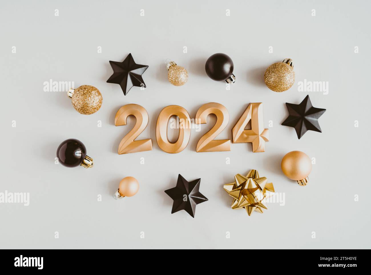 Biglietto d'auguri - felice anno nuovo con i numeri 2024 e palline di Natale dorate e nere decorate su sfondo chiaro. Concetto di vacanza minimalista. Vista dall'alto. Foto Stock