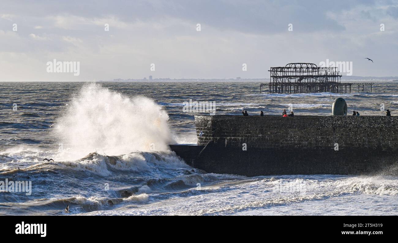 Brighton Regno Unito 5 novembre 2023 - i visitatori che guardano le onde che si infrangono su una groyne sul lungomare di Brighton mentre i venti più forti battono la costa meridionale oggi : Credit Simon Dack / Alamy Live News Foto Stock