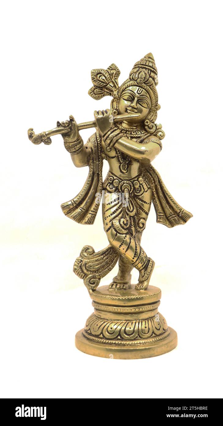 statua in ottone dorato del dio indù krishna in un abbigliamento rurale che suona il flauto isolato su uno sfondo bianco Foto Stock