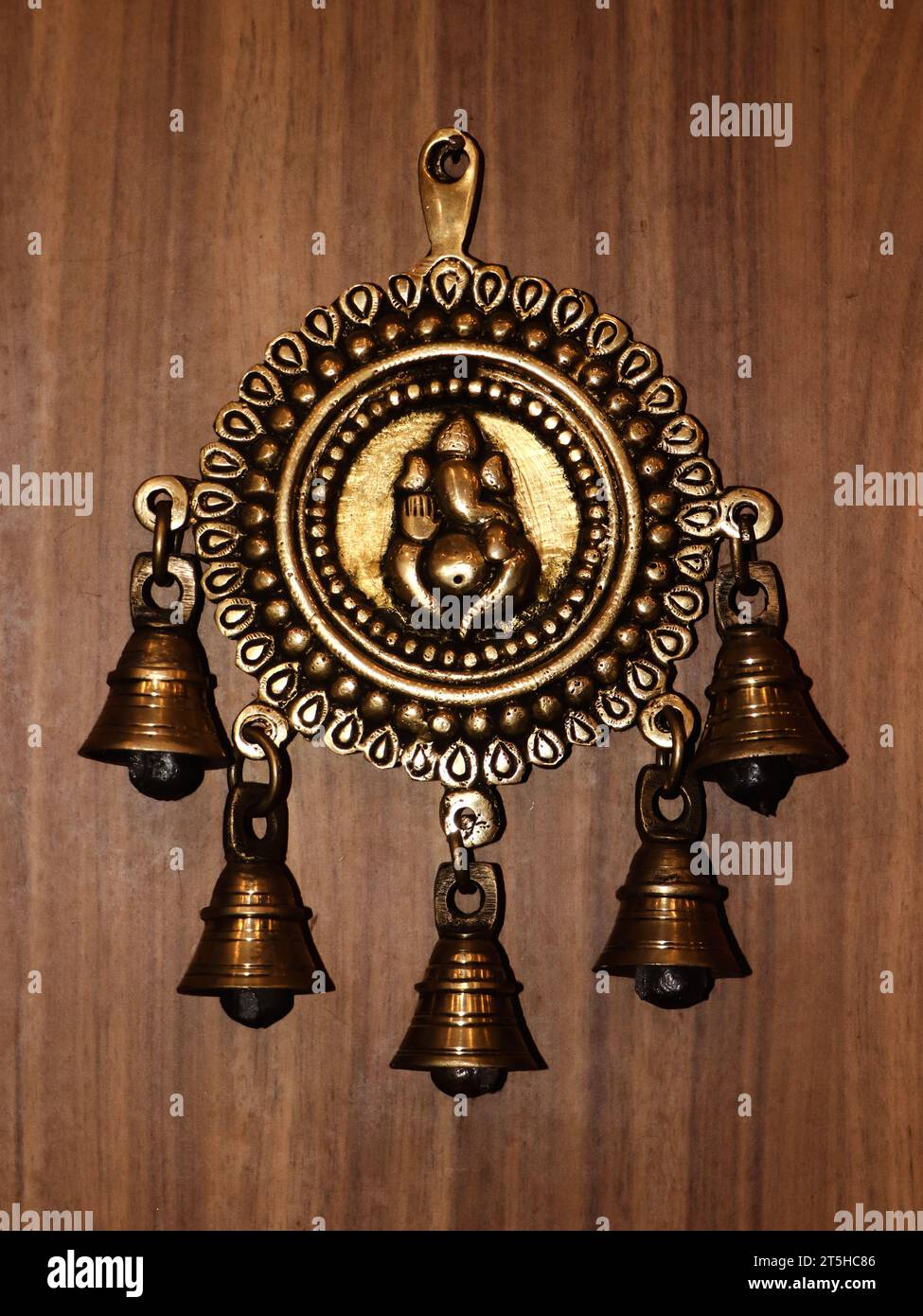 antiche campane in bronzo con una statua decorativa di ganesh su una parete di legno Foto Stock