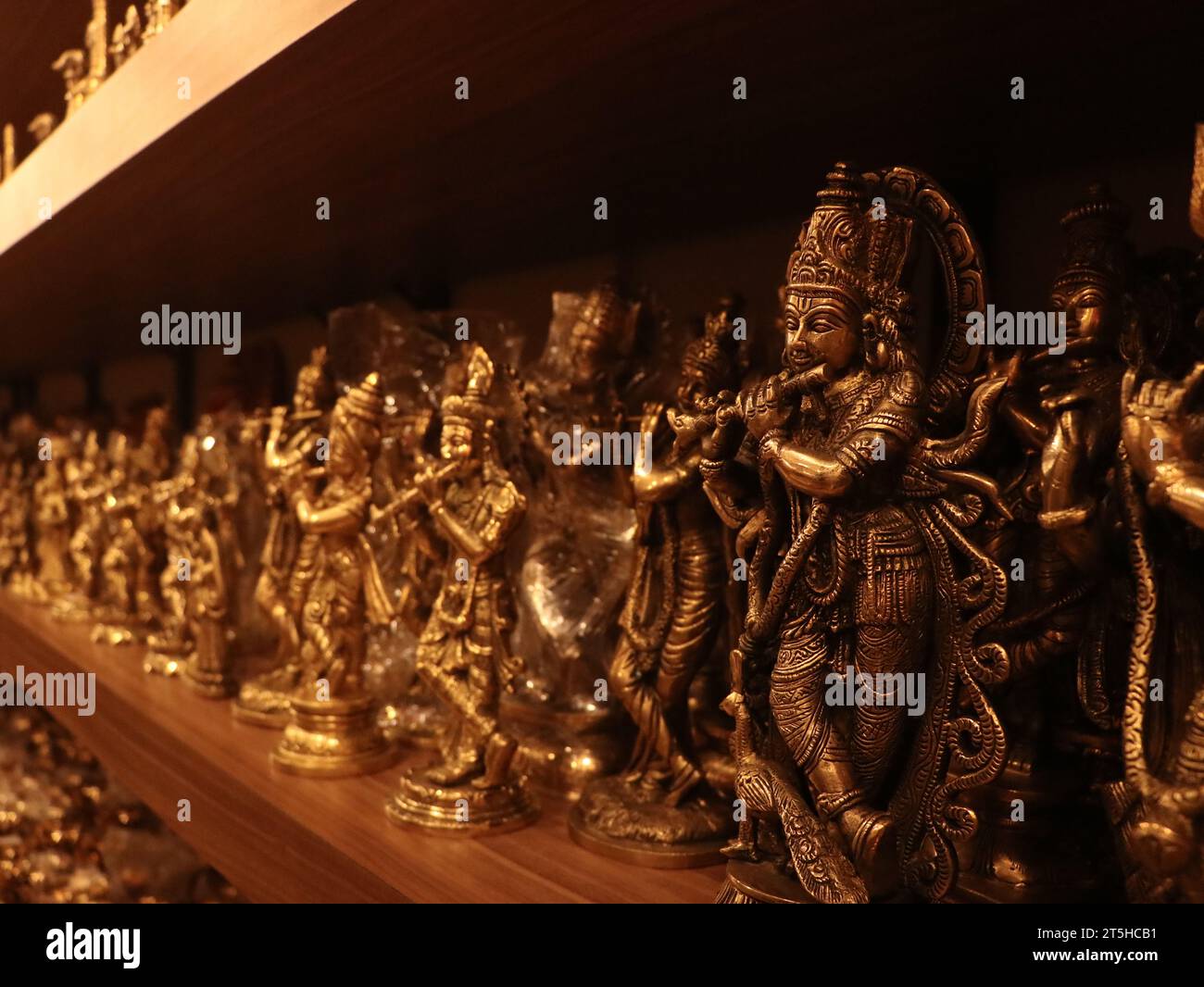 krishna, il signore artigianale, che suona gli idoli del flauto conservati per essere esposti su uno scaffale di un negozio di souvenir religioso vicino al tempio Foto Stock