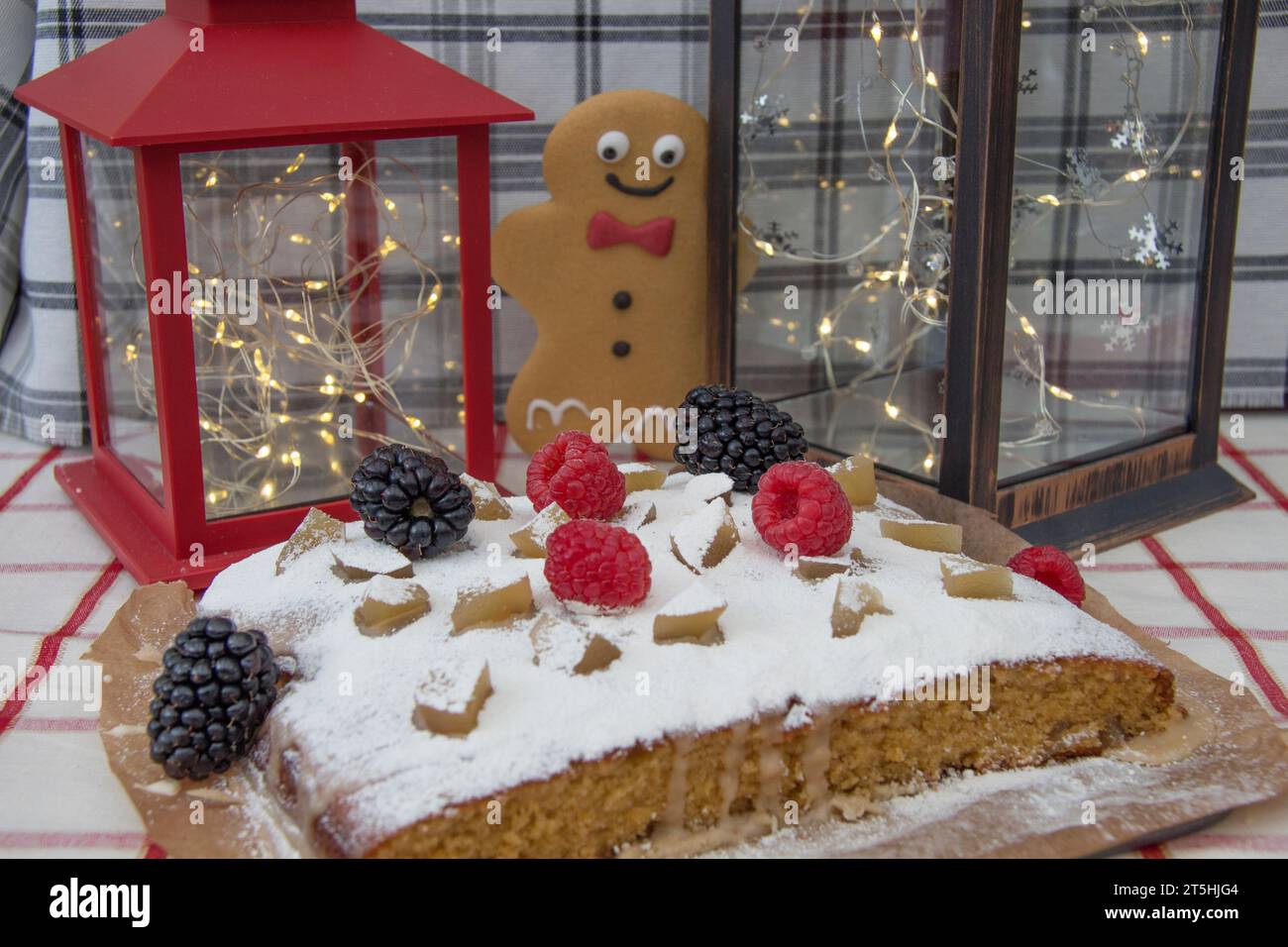 Joyful Gingerbread Man trova una deliziosa torta con decorazioni e frutta Foto Stock