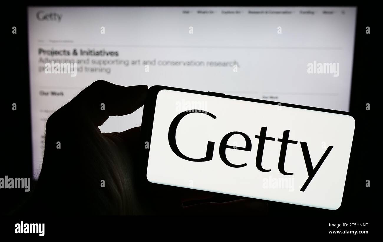 Persona in possesso di un cellulare con il logo della fondazione d'arte statunitense J. Paul Getty Trust davanti alla pagina web. Concentrarsi sul display del telefono. Foto Stock