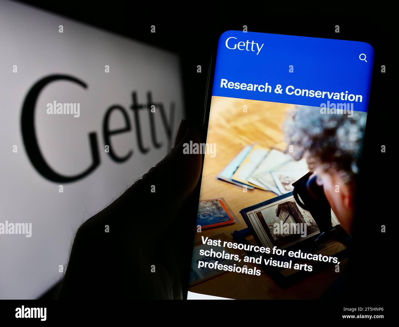 Persona che possiede un telefono cellulare con una pagina Web della fondazione d'arte statunitense J. Paul Getty Trust davanti al logo. Concentrarsi sul centro del display del telefono. Foto Stock
