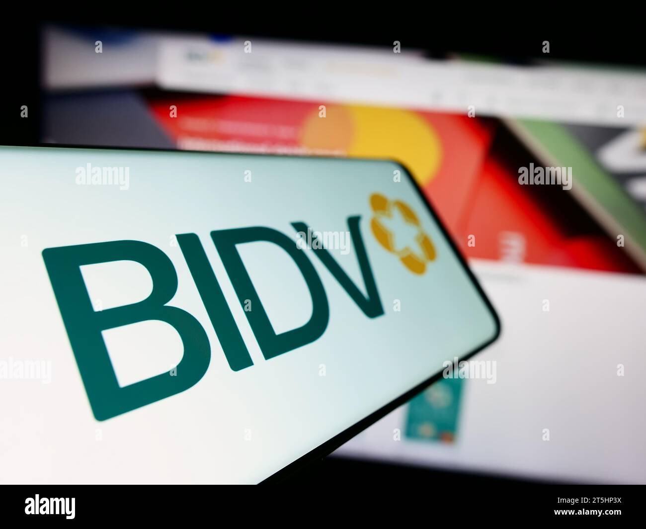 Telefono cellulare con logo della Commercial Bank for Investment and Development of Vietnam davanti al sito web. Mettere a fuoco il display centrale sinistro del telefono. Foto Stock
