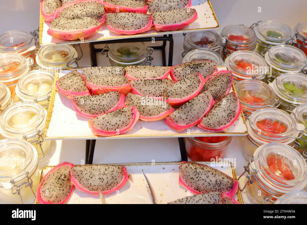 una mostra di frutti di drago quarti (pitahaya) che mostra la sua carne bianca e i semi neri Foto Stock