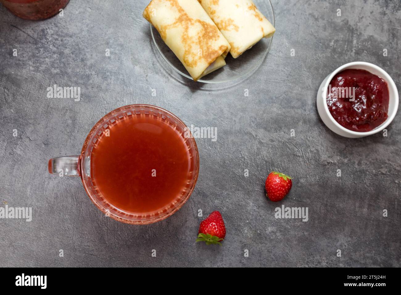 una tazza di tè alla frutta, pancake con ripieno di frutti di bosco e fragole su un tavolo grigio scuro. vista dall'alto. Foto Stock