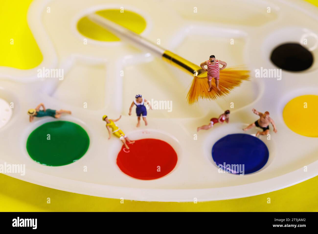 Persone in miniatura che hanno una giornata in spiaggia su una tavolozza di pitture artistiche Foto Stock