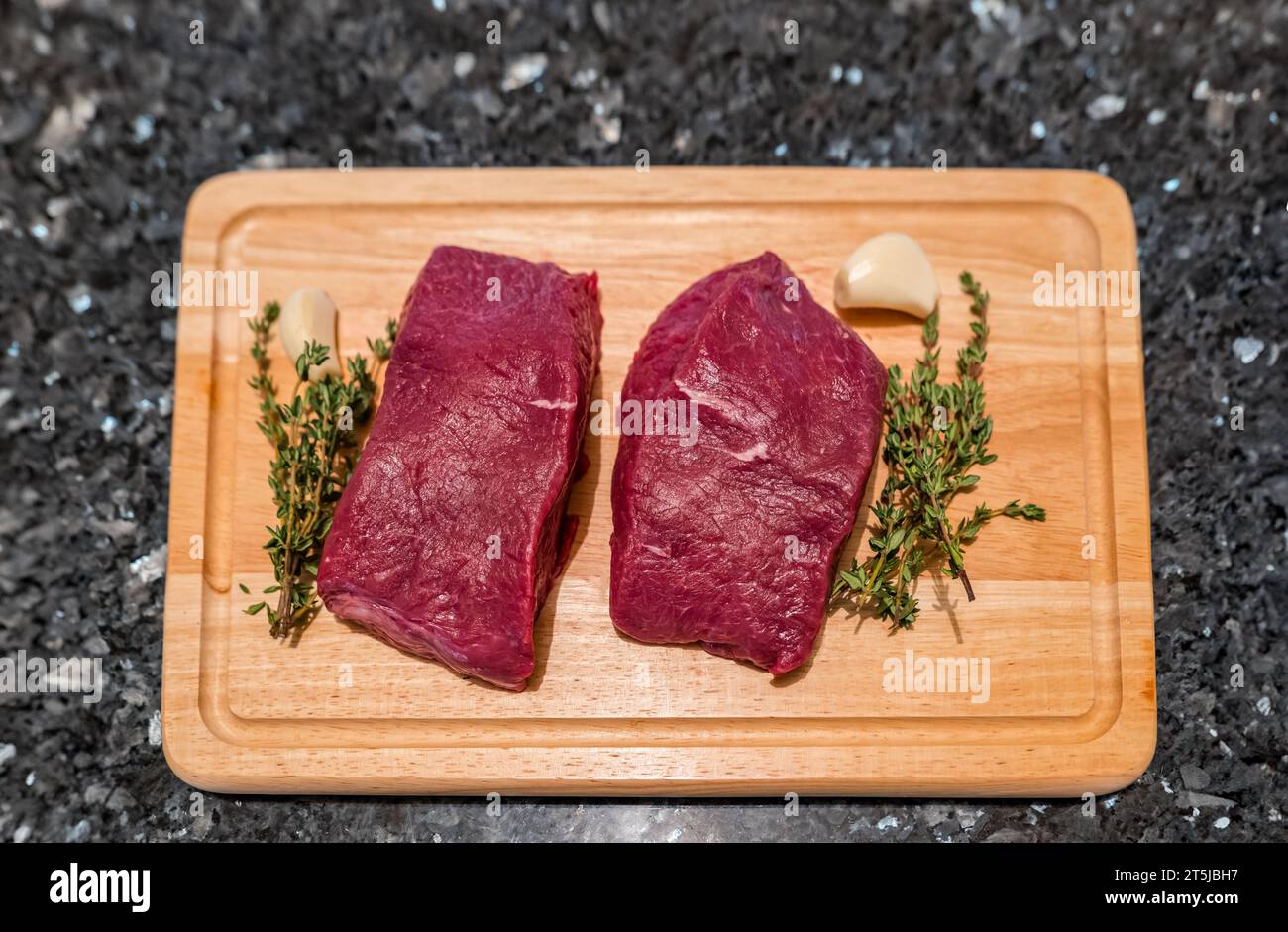 Due bistecche di veleno in preparazione per la cottura su tagliere con timo e aglio Foto Stock