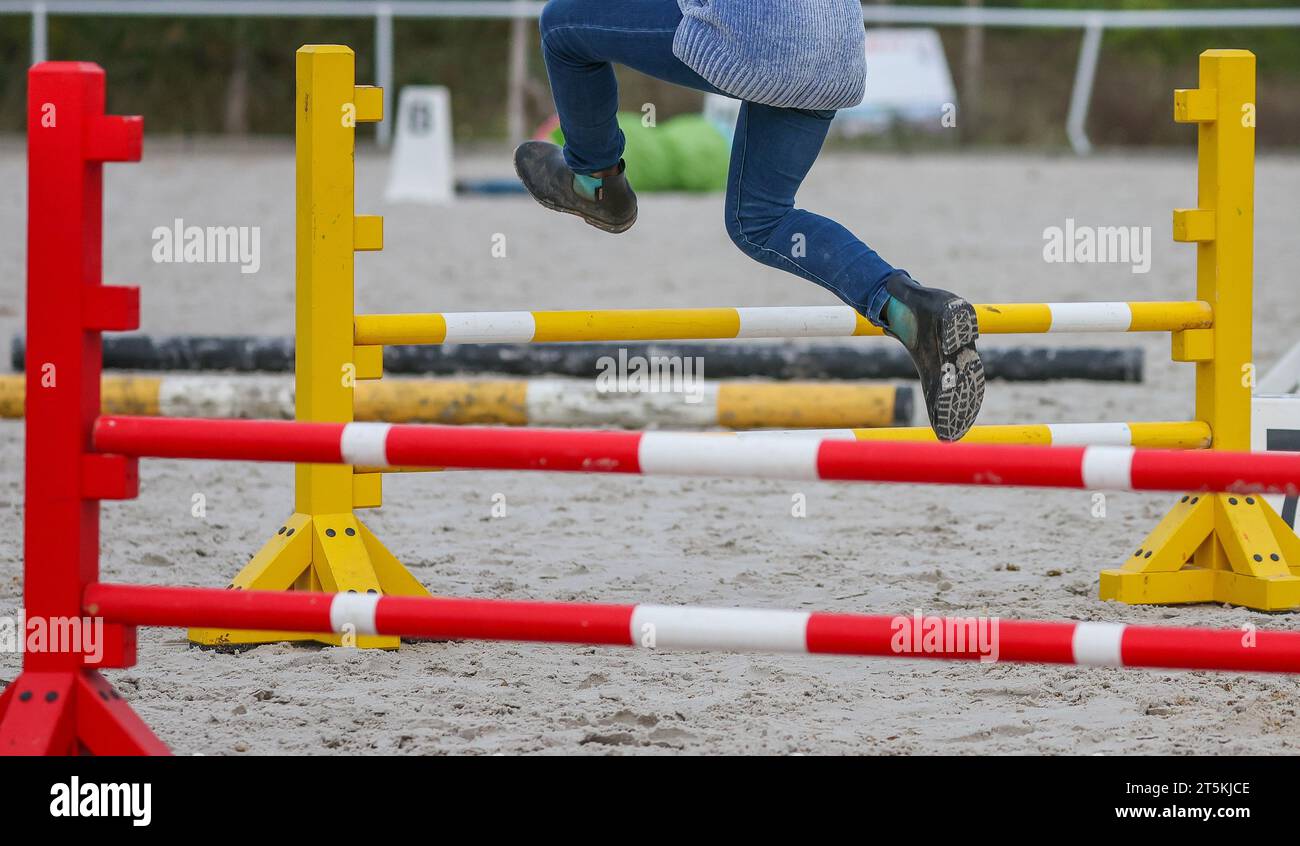 Halle, Germania. 3 novembre 2023. Lucie salta su un ostacolo sul suo cavallo da hobby Sunny. Insieme ad altre persone che condividono la stessa mentalità, il bambino di nove anni partecipa a "Hobbyhorsing" presso l'Halle (Saale) Riding Club. Gli atleti corrono attraverso un percorso di salto ostacoli su cavalli da hobby o eseguono un test di dressage. Gli hobbyhorse possono timido o rifiutarsi di saltare proprio come i loro grandi modelli di ruolo. Crediti: Jan Woitas/dpa/Alamy Live News Foto Stock