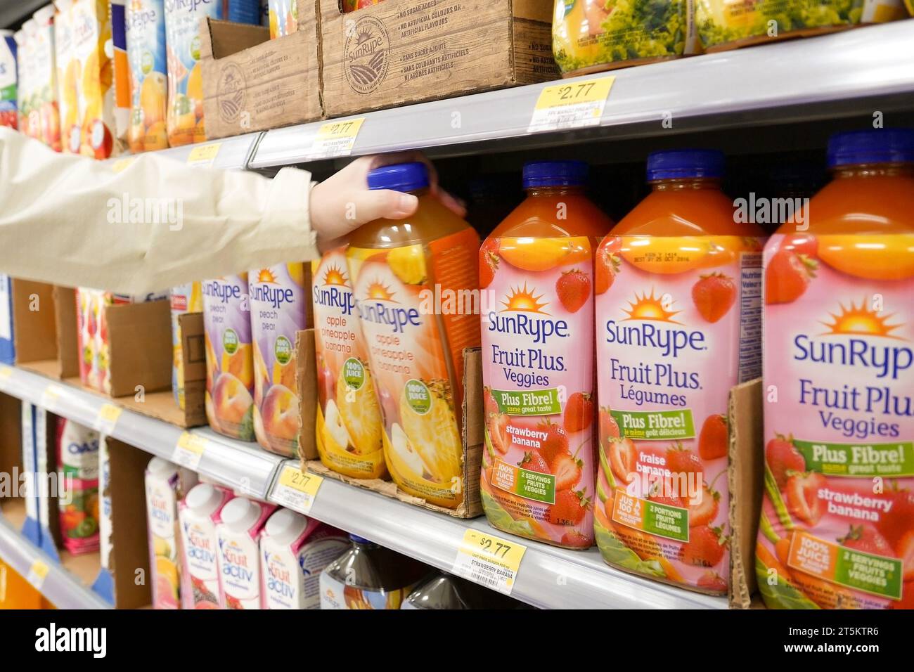 Donna che acquista succo di frutta Sunrype e verdure in un negozio Walmart Foto Stock