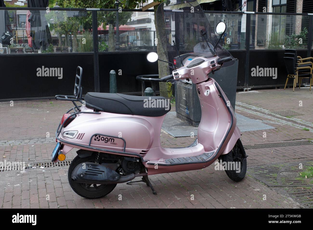 Assen, Paesi Bassi - 11 ottobre 2023 Uno scooter rosa AGM VX50i parcheggiato di fronte a un ristorante Foto Stock