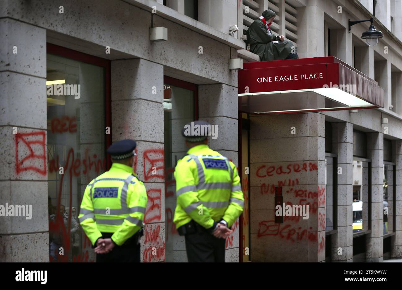 Gli agenti di polizia tengono d'occhio un attivista che siede sulla tettoia degli uffici di Leonardo. Gli attivisti di Palestine Action occupano e prendono di mira il gigante italiano dell'industria degli armamenti Leonardo nel loro quartier generale di Londra e li chiudono. Leonardo rifornisce Israele con jet da combattimento e armi attualmente in uso a Gaza. Palestine Action chiede che le compagnie di armamento che forniscono armi a Israele chiudano definitivamente. Hanno annunciato che le società che vendono armi alla forza di difesa israeliana e alle loro società partner saranno prese di mira con azioni dirette. Queste azioni hanno lo scopo di evidenziare Foto Stock