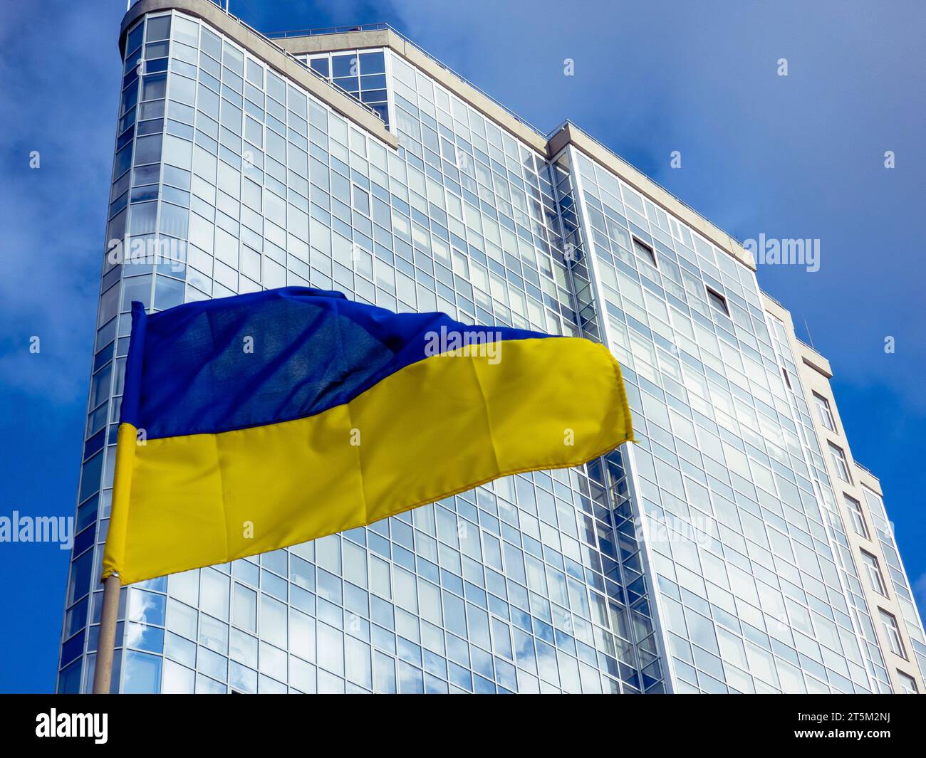 Una vibrante bandiera Ucraina che sventola contro un edificio moderno Foto Stock