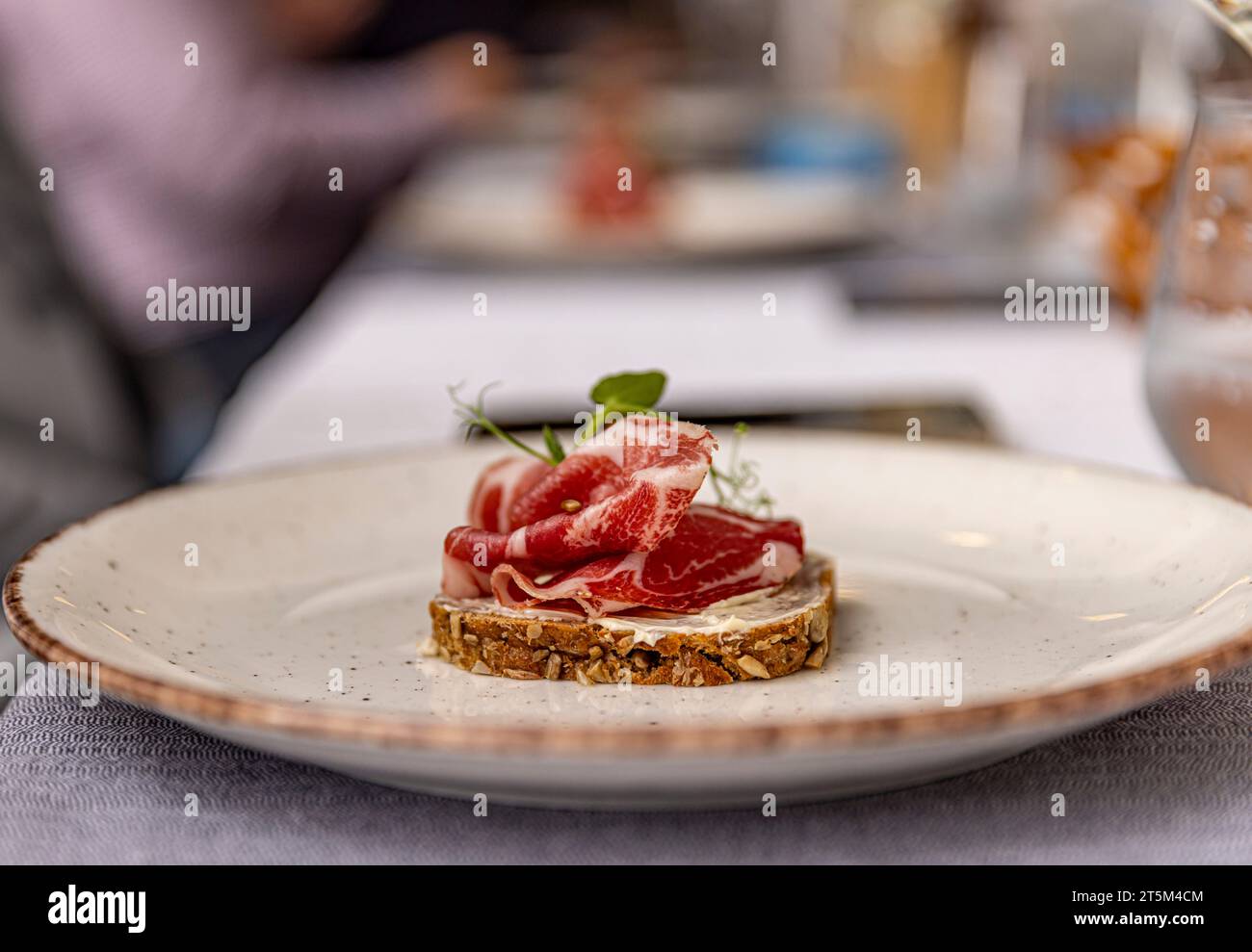 Prosciutto a fette sottili, elegantemente disposto su un pane Foto Stock