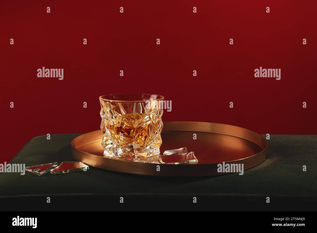 Bicchiere di bevanda alcolica e frammenti di specchio rotto su superficie morbida Foto Stock