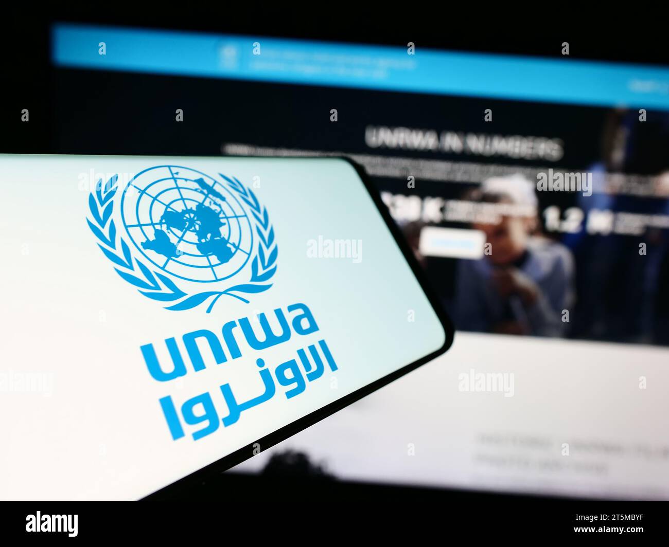 Smartphone con logo dell'agenzia delle Nazioni Unite per i rifugiati plalestini UNRWA davanti al sito web. Mettere a fuoco il display centrale sinistro del telefono. Foto Stock