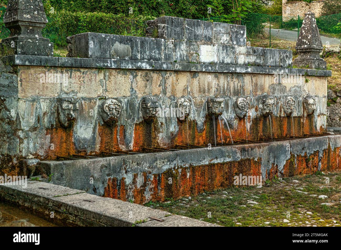 Fontana romana vicino all'antico borgo, è composta da diversi beccucci che scorrono da volti umani in pietra. Pescosansonesco, provincia di Pescara, Abruzzo Foto Stock