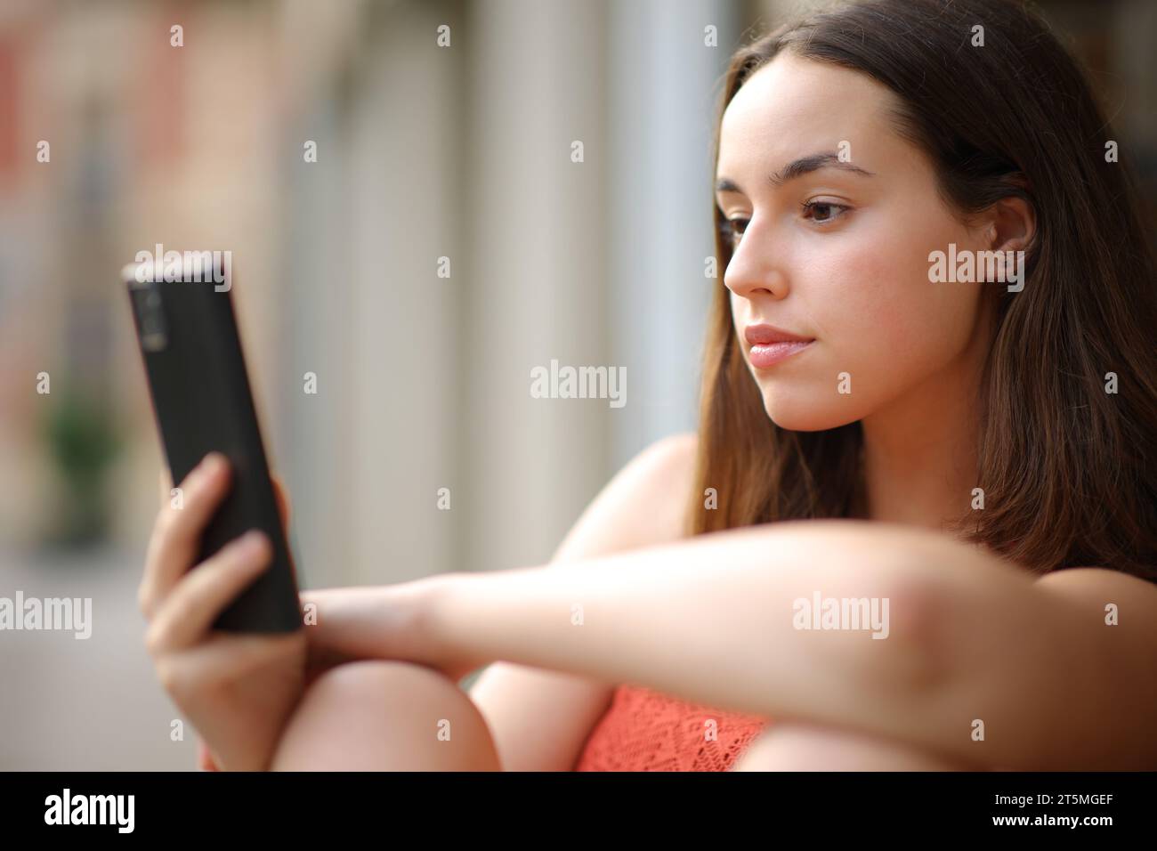 Donna seria che controlla i contenuti del telefono all'aperto in strada Foto Stock