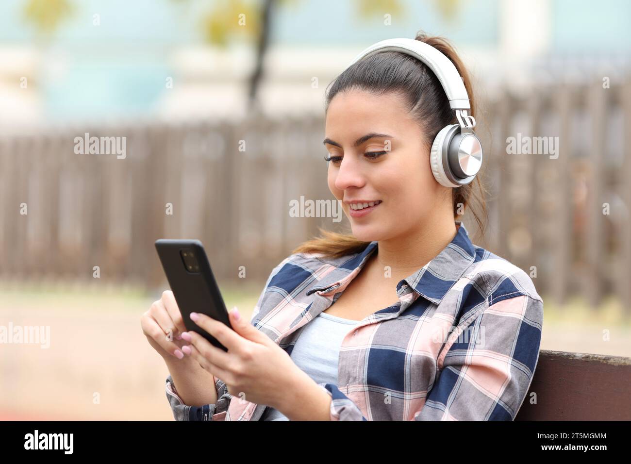 Felice adolescente che ascolta musica in una panchina Foto Stock
