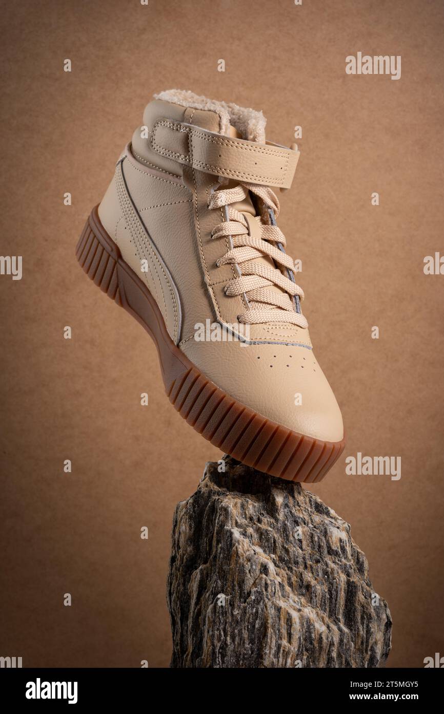 Stivali casual in pelle beige su sfondo marrone. Сreative fotografia per un poster pubblicitario per pubblicità di calzature Foto Stock