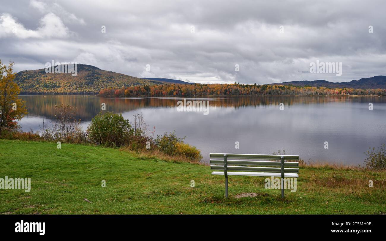 Una panchina che si affaccia sul Wood Pond nel Pommerlo Memorial Park, Jackman, Maine. Foto Stock