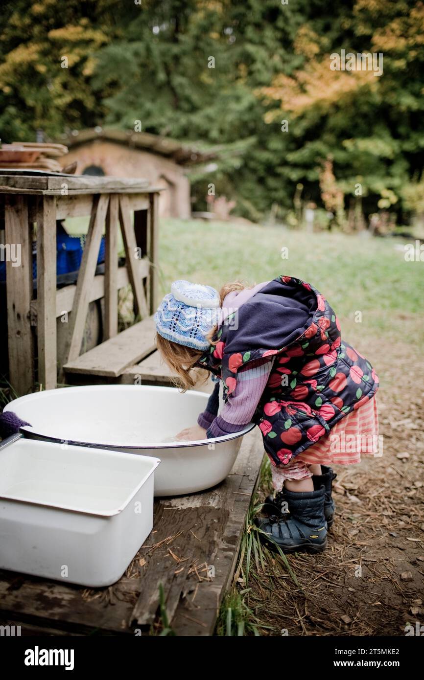 Una ragazza dai capelli rossi in gruppo per il freddo si lava le mani in un lavandino. Foto Stock