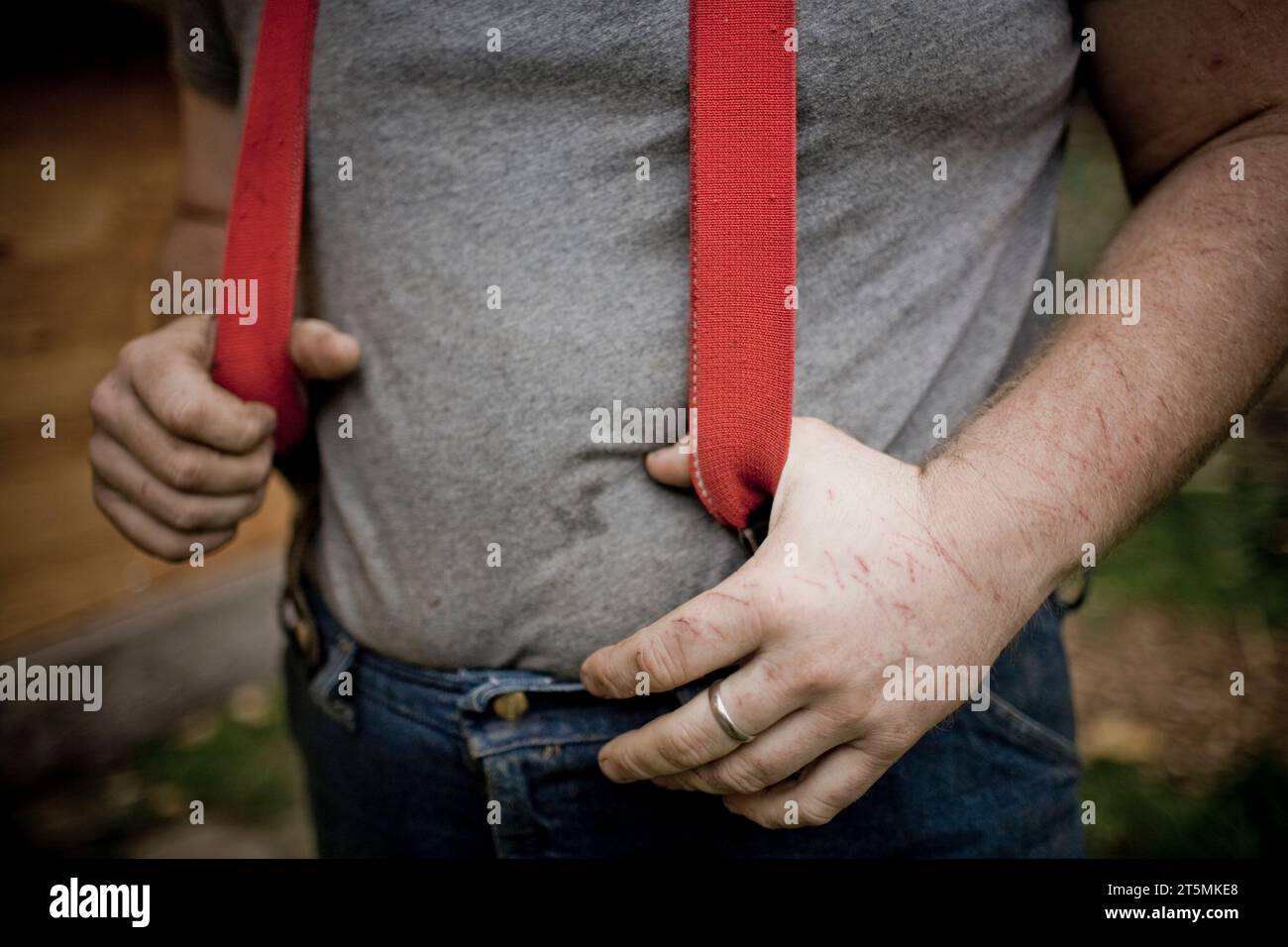 Un giovane uomo che indossa delle bretelle rosse in una fattoria. Foto Stock