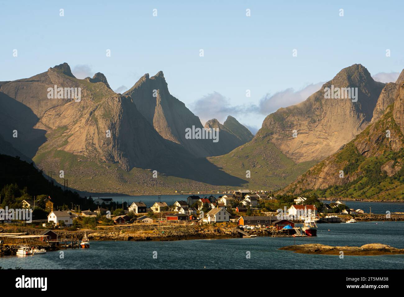 Il tipico villaggio di pescatori di Reine, Lofoten, Norvegia, in una giornata di sole con montagne sullo sfondo, cieli azzurri e mare blu. Foto Stock