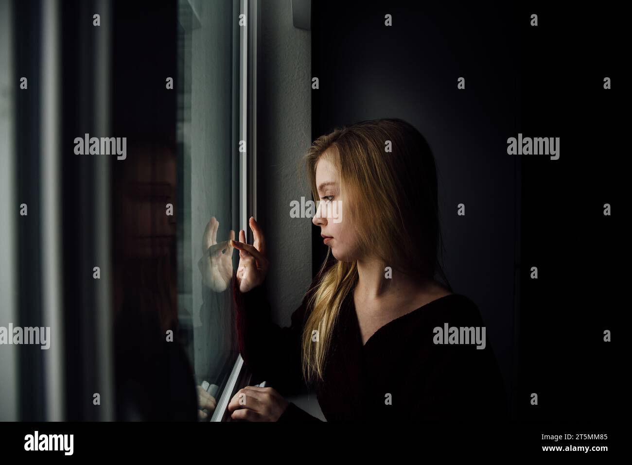 Una seria preadolescente disegna sulla finestra mentre guarda la mano con Foto Stock