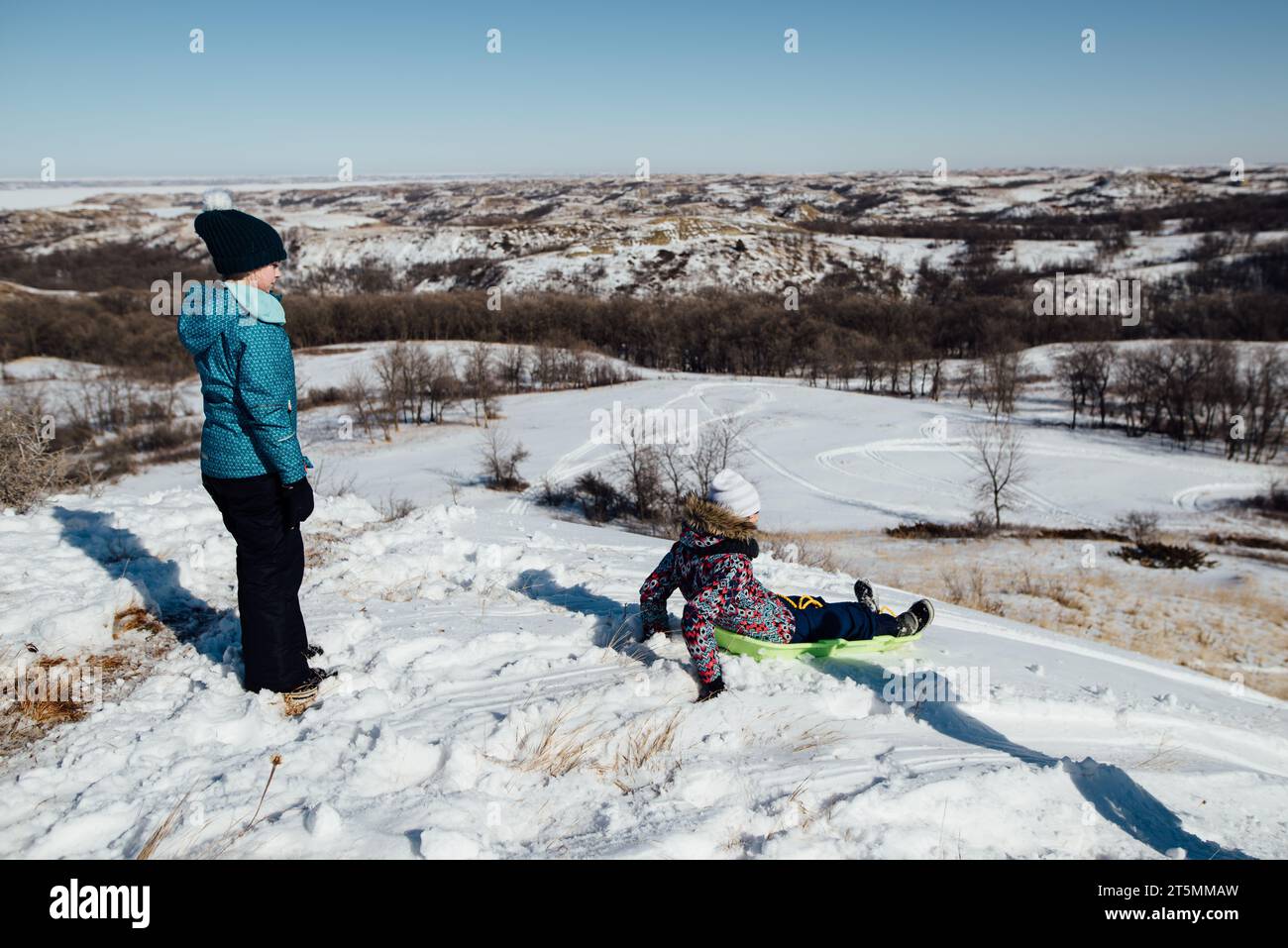 Ampia veduta delle ragazze in slitta sulla cima di una collina nella splendida campagna di sno Foto Stock