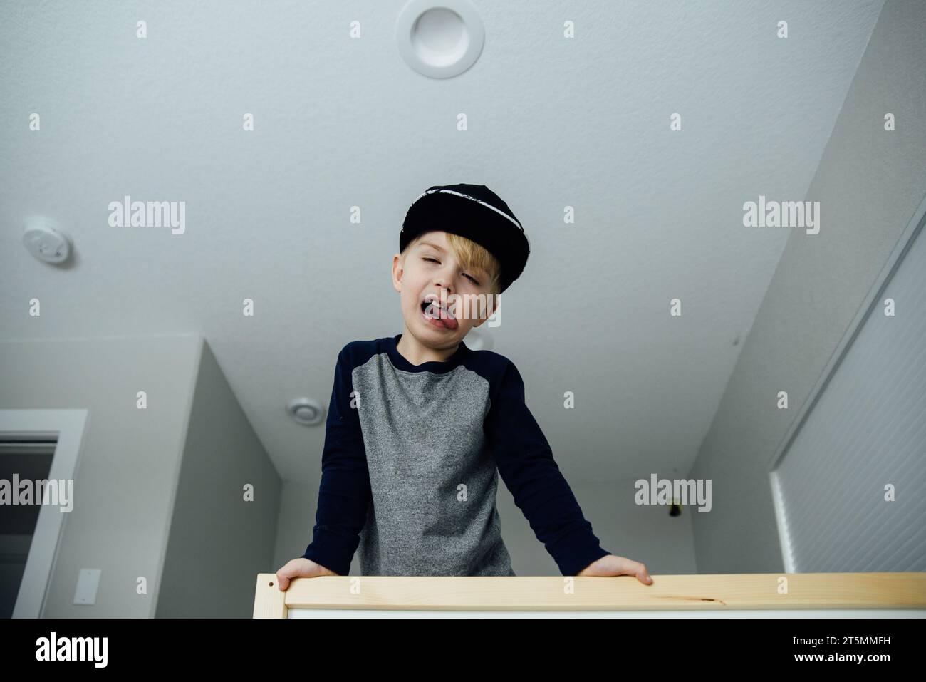 Vista bassa di un ragazzo che si piega sopra una ringhiera che sporge dalla lingua e da mak Foto Stock