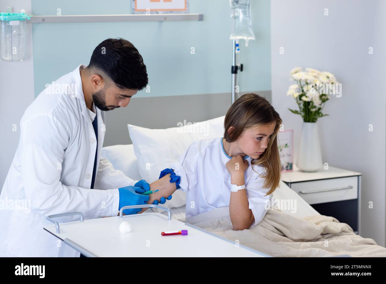 Mirato diverso medico maschile che prende il campione di sangue con siringa da ragazza paziente in letto d'ospedale Foto Stock