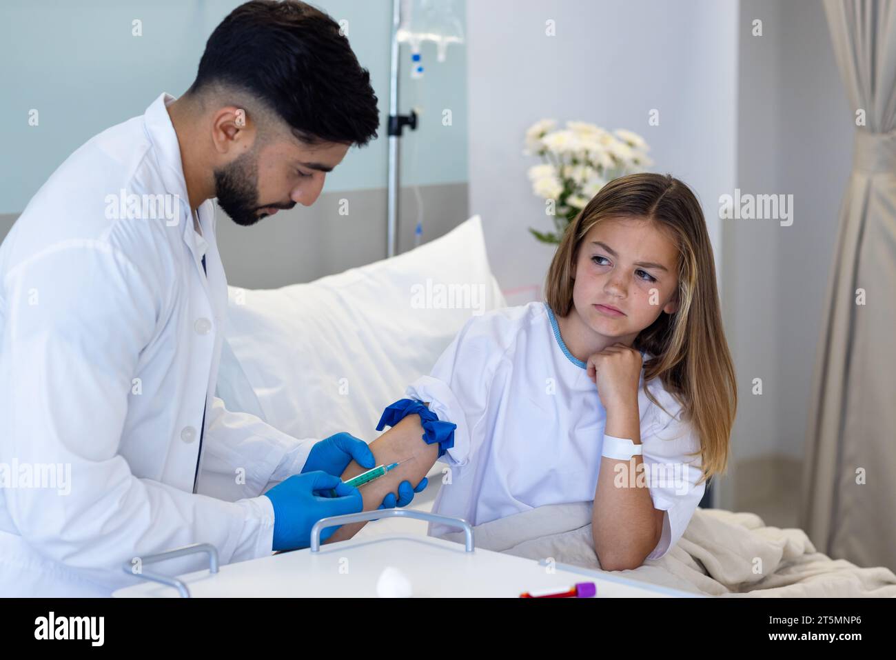 Mirato diverso medico maschile che prende il campione di sangue con siringa da ragazza paziente in letto d'ospedale Foto Stock