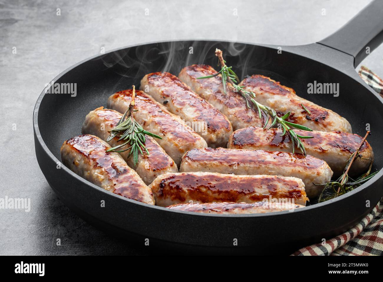 Deliziose salsicce di maiale in padella su sfondo grigio Foto Stock