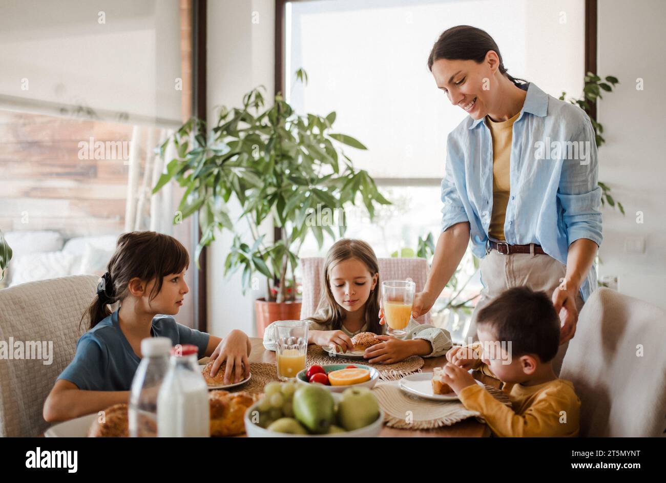 La madre prepara la colazione per i bambini, al mattino. Amore materno e cura per la famiglia e la famiglia. Foto Stock