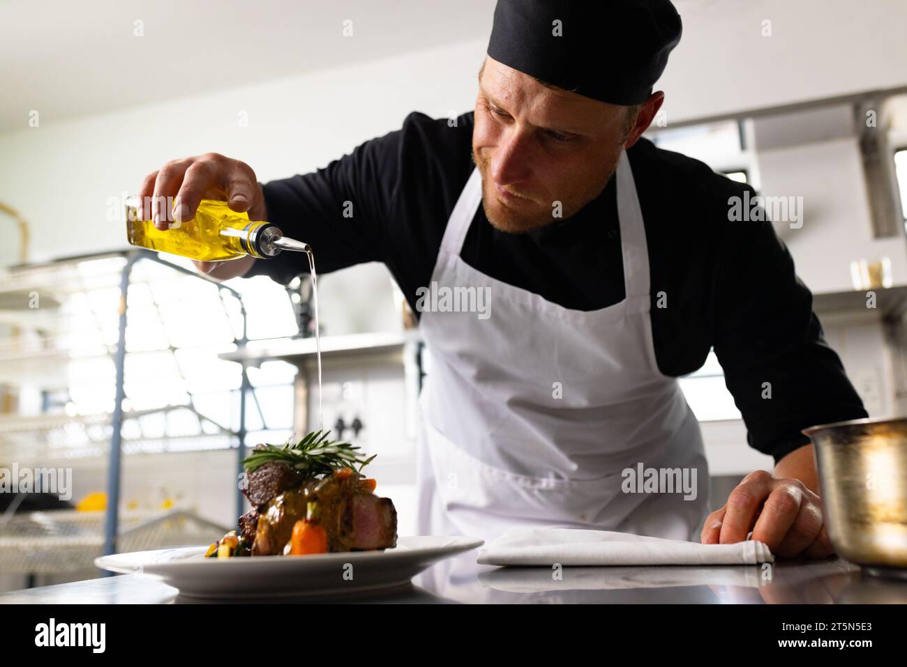 Felice chef maschio caucasico che prepara il pasto al piatto nella cucina del ristorante Foto Stock