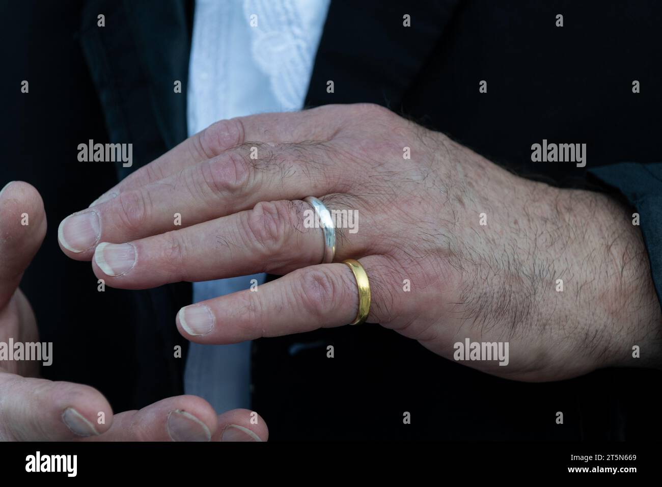 Un uomo mette gli anelli della sposa e dello sposo sulle dita per la custodia prima dello scambio di anelli cerimonia in un matrimonio ebraico. Foto Stock