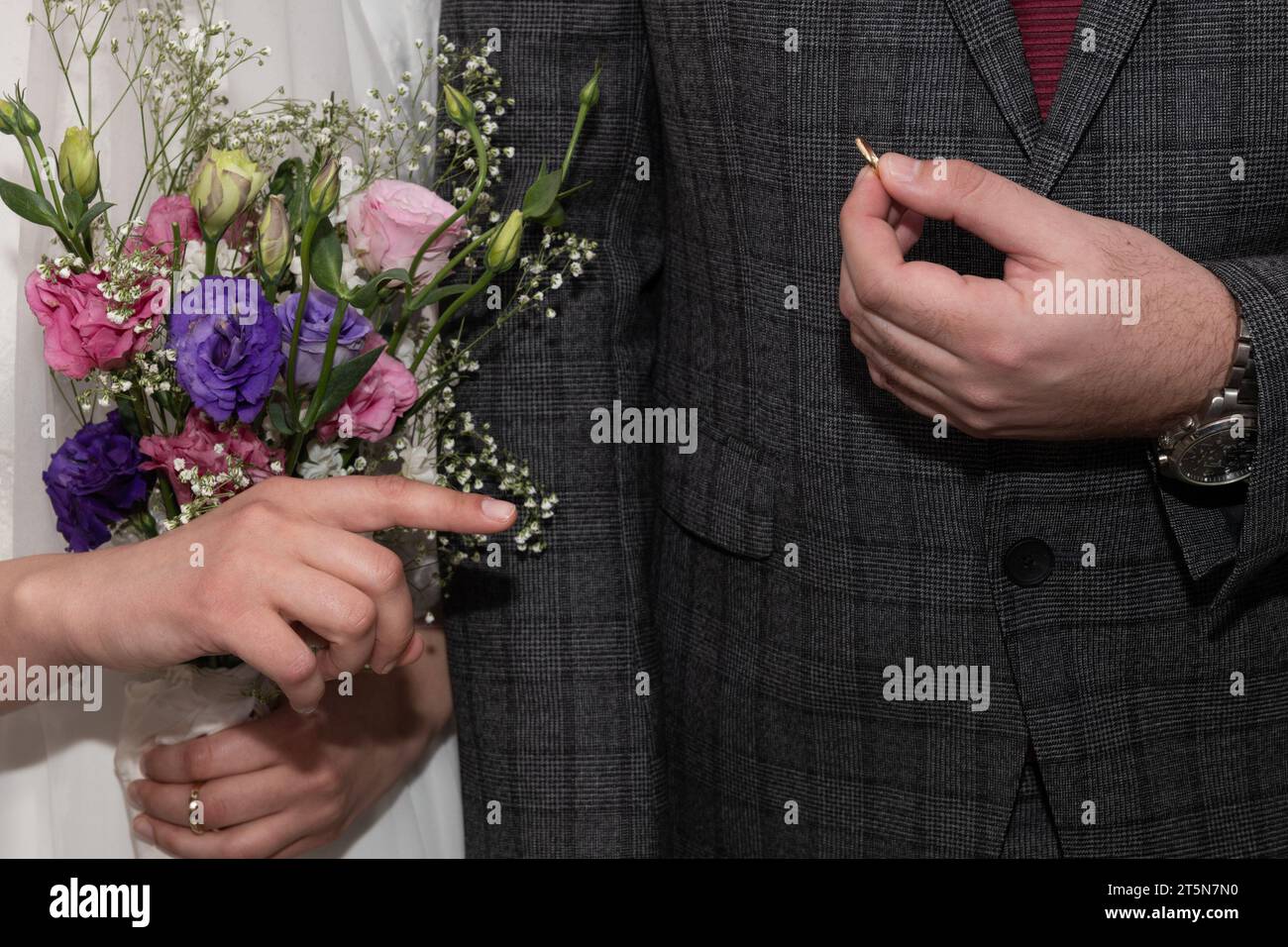 Uno sposo mostra l'anello che ha acquistato per la sua sposa e si prepara a metterlo sul dito durante la cerimonia di scambio o anelli di un matrimonio ebraico. Foto Stock
