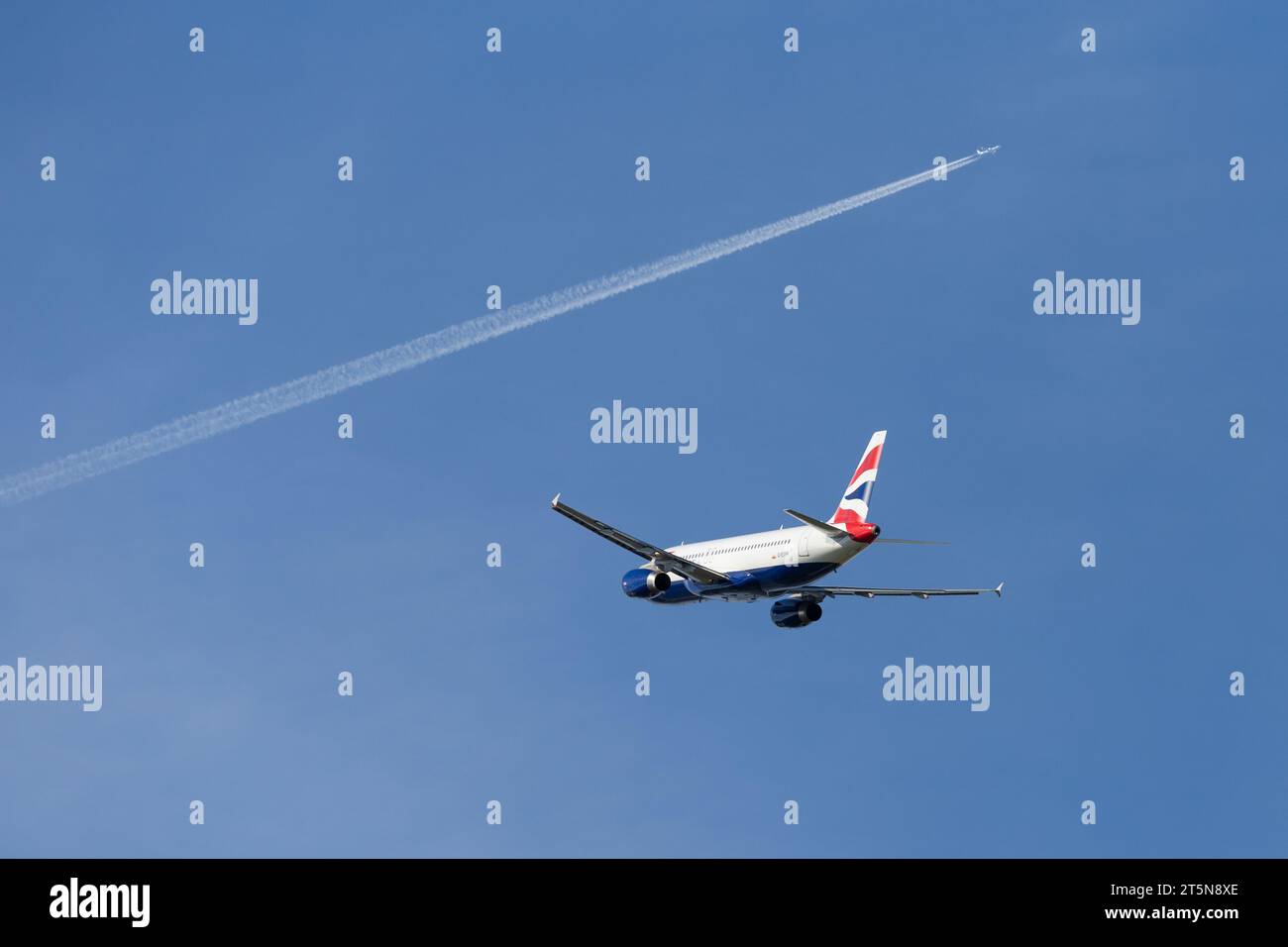 British Airways Airbus A320-232, immatricolazione G-EUYH in partenza da Londra Heathrow in un soleggiato tardo pomeriggio con un contrail e un altro aereo in lontananza Foto Stock