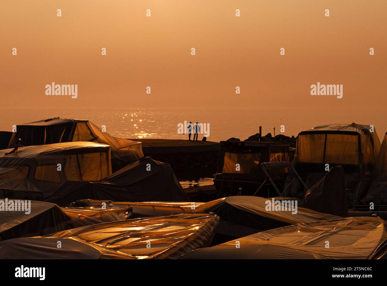 Caratterizzata dall'amicizia, incorniciata dal mare. Un legame ininterrotto oltre le barche rotte. Due maschi che parlano al tramonto. Foto Stock