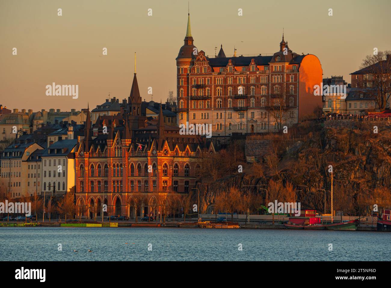 Vecchi edifici nel centro di Stoccolma al tramonto, affacciati sul lago, in una tranquilla giornata invernale. Foto Stock
