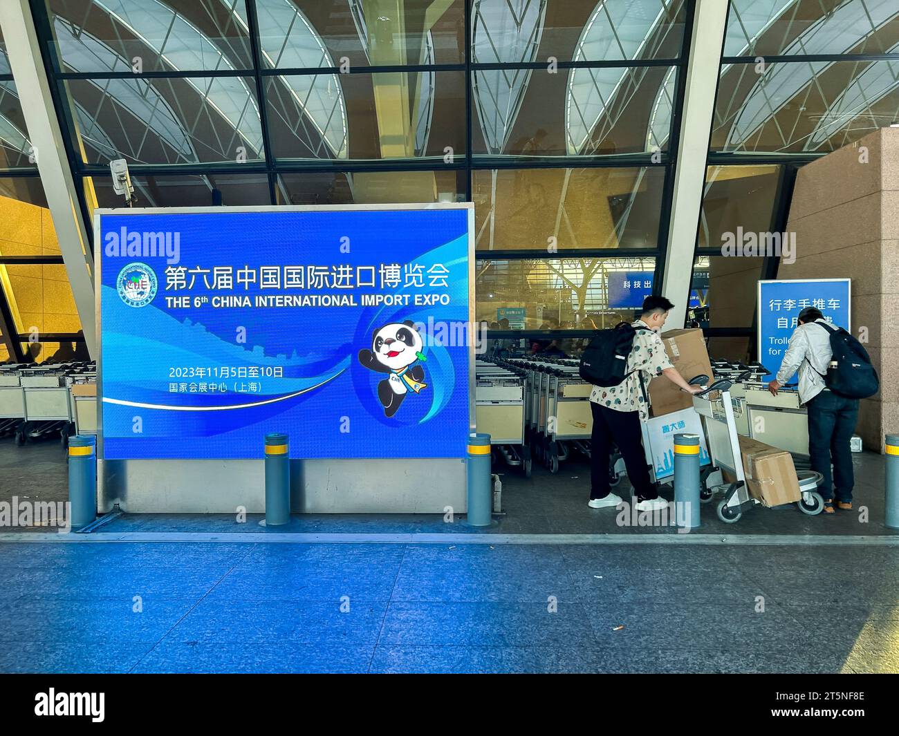 Shanghai, Cina, uomini che viaggiano, vedute fuori dall'Aeroporto Internazionale di Pudong, poster di viaggio per il cartello "China International Import Expo" Foto Stock