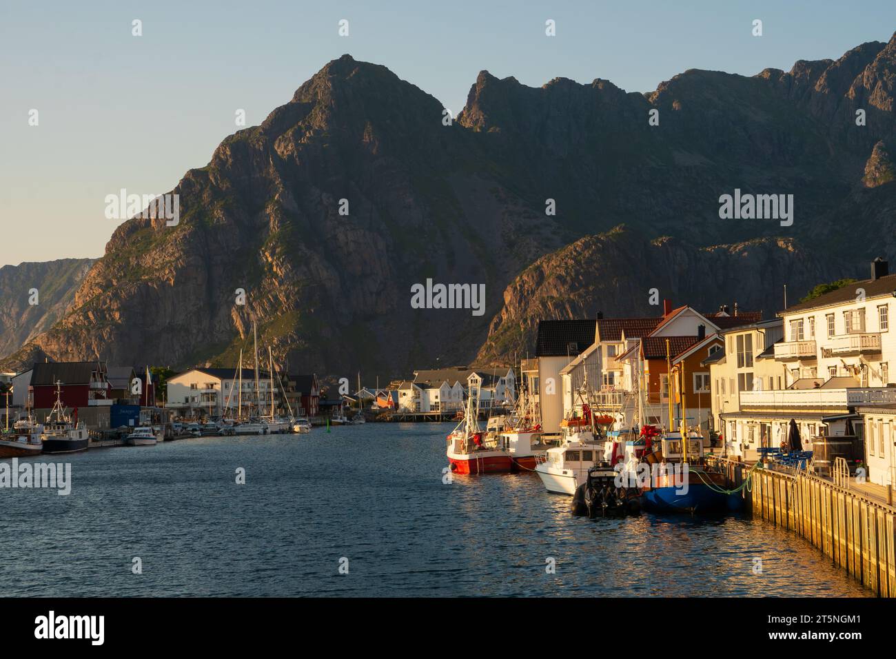 Il porto di Henningsvaer a Lofoten, Norvegia, al sole di tarda sera d'estate, con case e barche Foto Stock