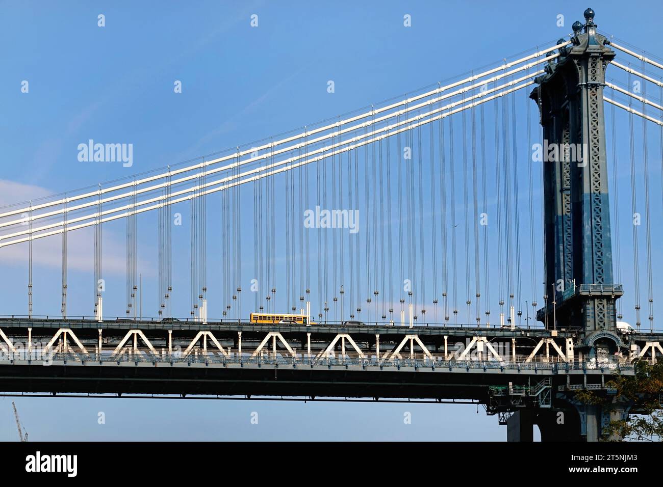 Un iconico autobus giallo attraversa il ponte sospeso di Manhattan Foto Stock