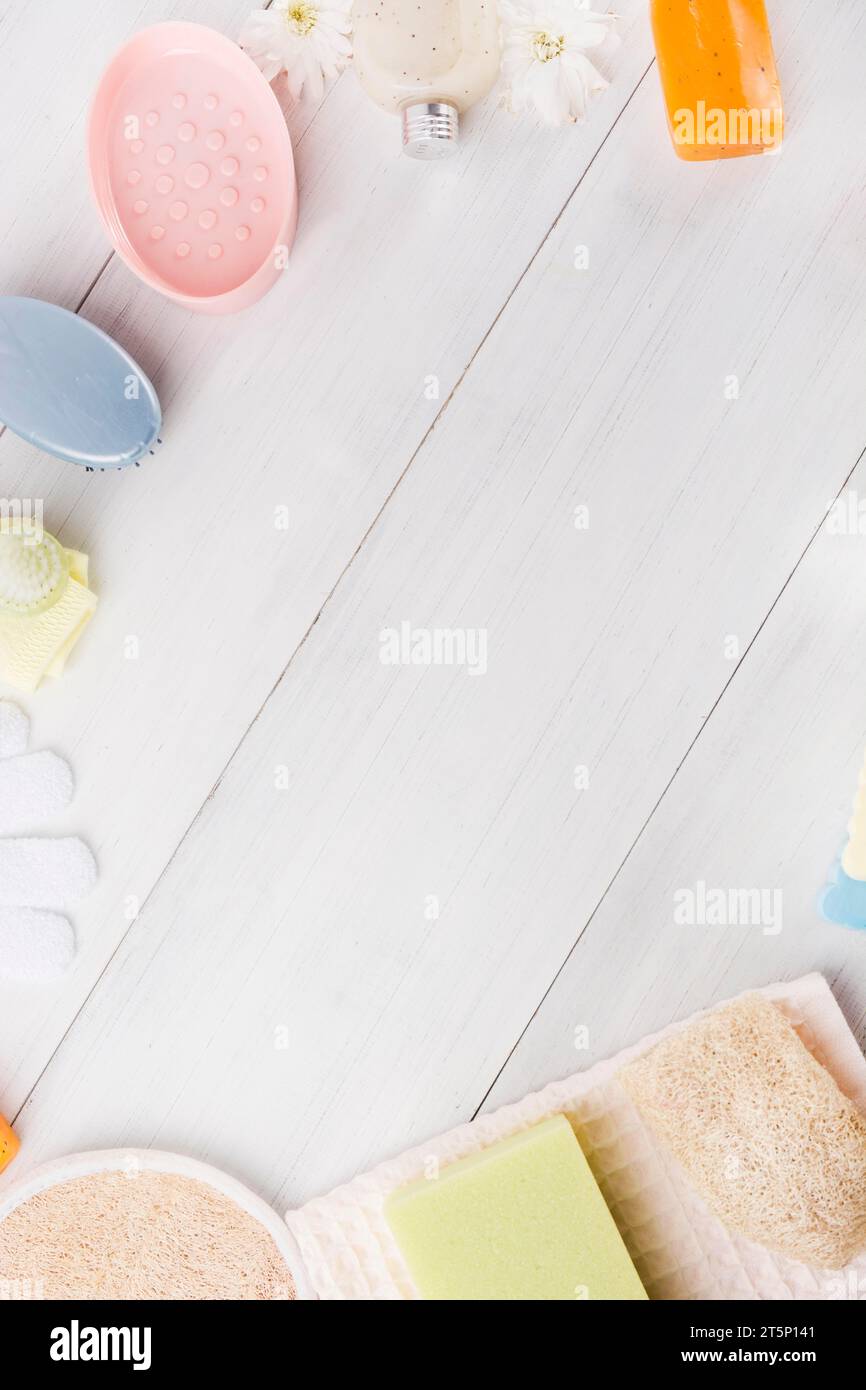 Spugna vista dall'alto sapone alle erbe, tovagliolo, guanti, spazzola massaggiante, fiore di loofah, tavola in legno con testo di scrittura spaziale Foto Stock