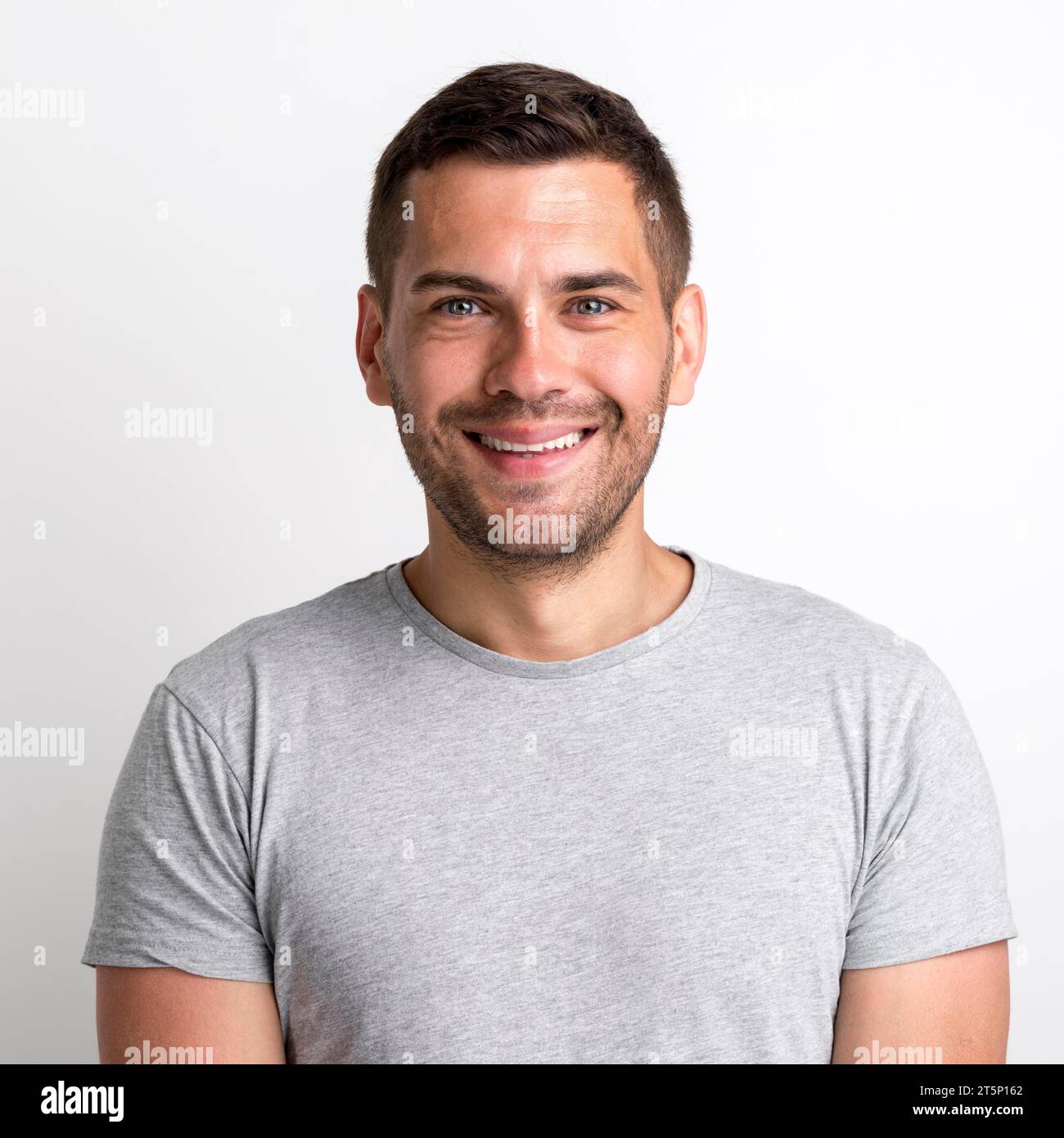 Ritratto sorridente e affascinante T-shirt grigia giovane uomo su sfondo semplice Foto Stock